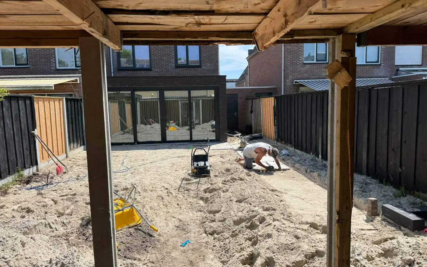 Zicht vanonder de houten overkapping op de tuin in aanleg