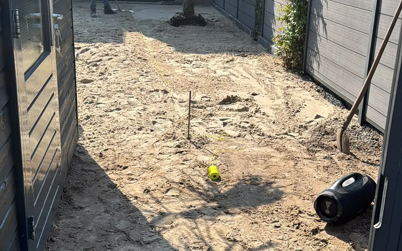 Dezelfde tuin tijdens de aanleg, uitgevlakt zand tussen de schuttingen