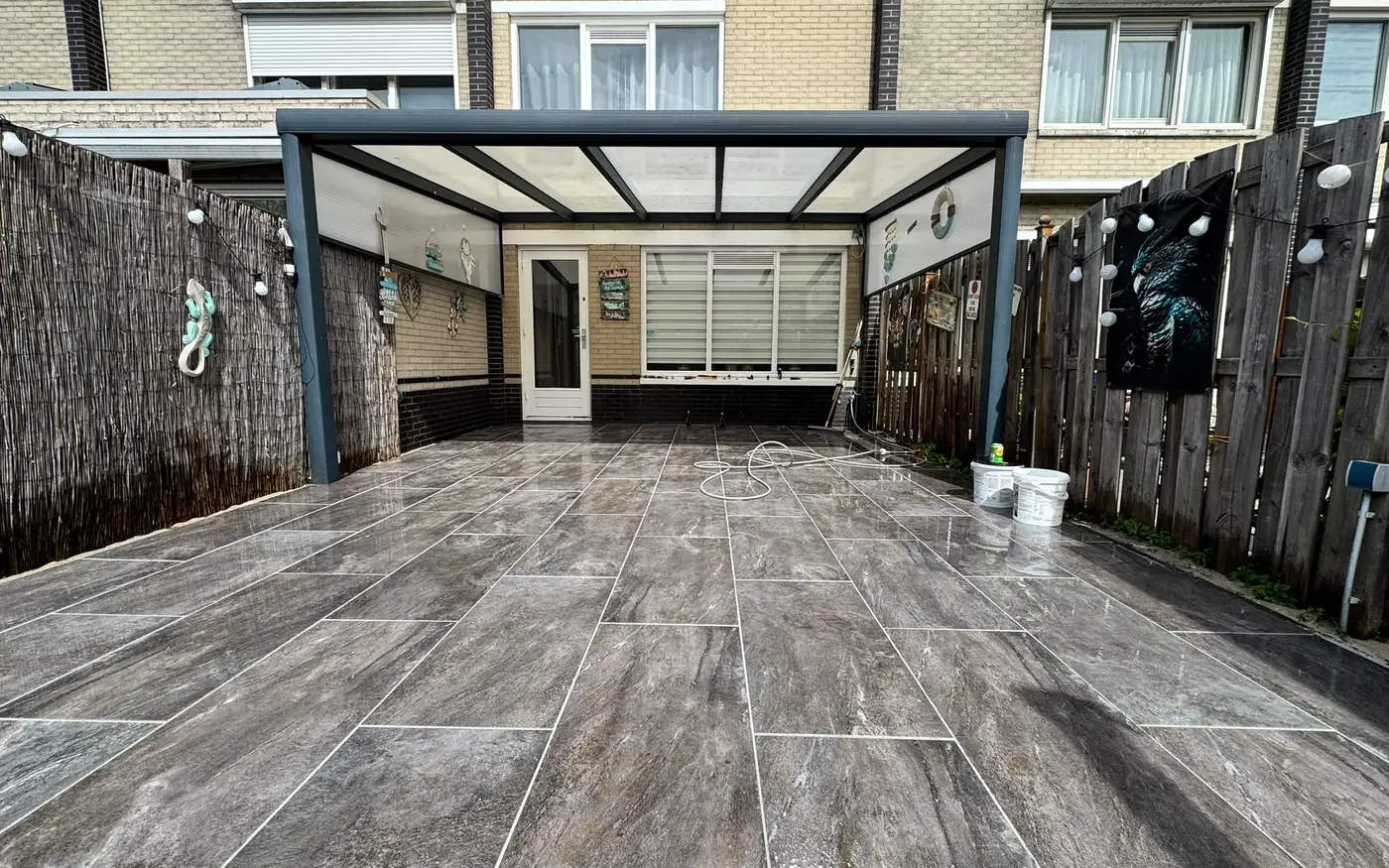 Veranda met glazen dak boven het afgewerkte marmerlook terras